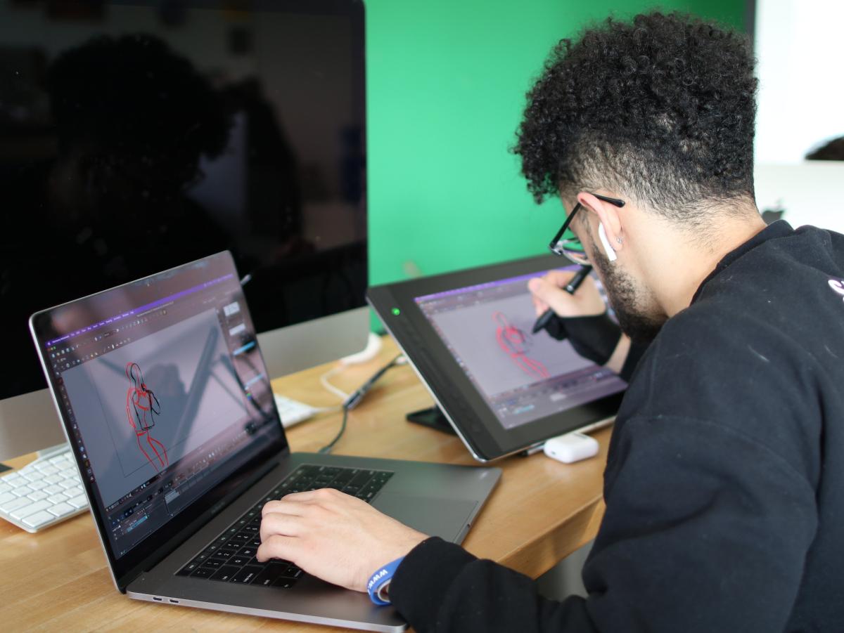 A student using a drawing tablet and computer for digital animation