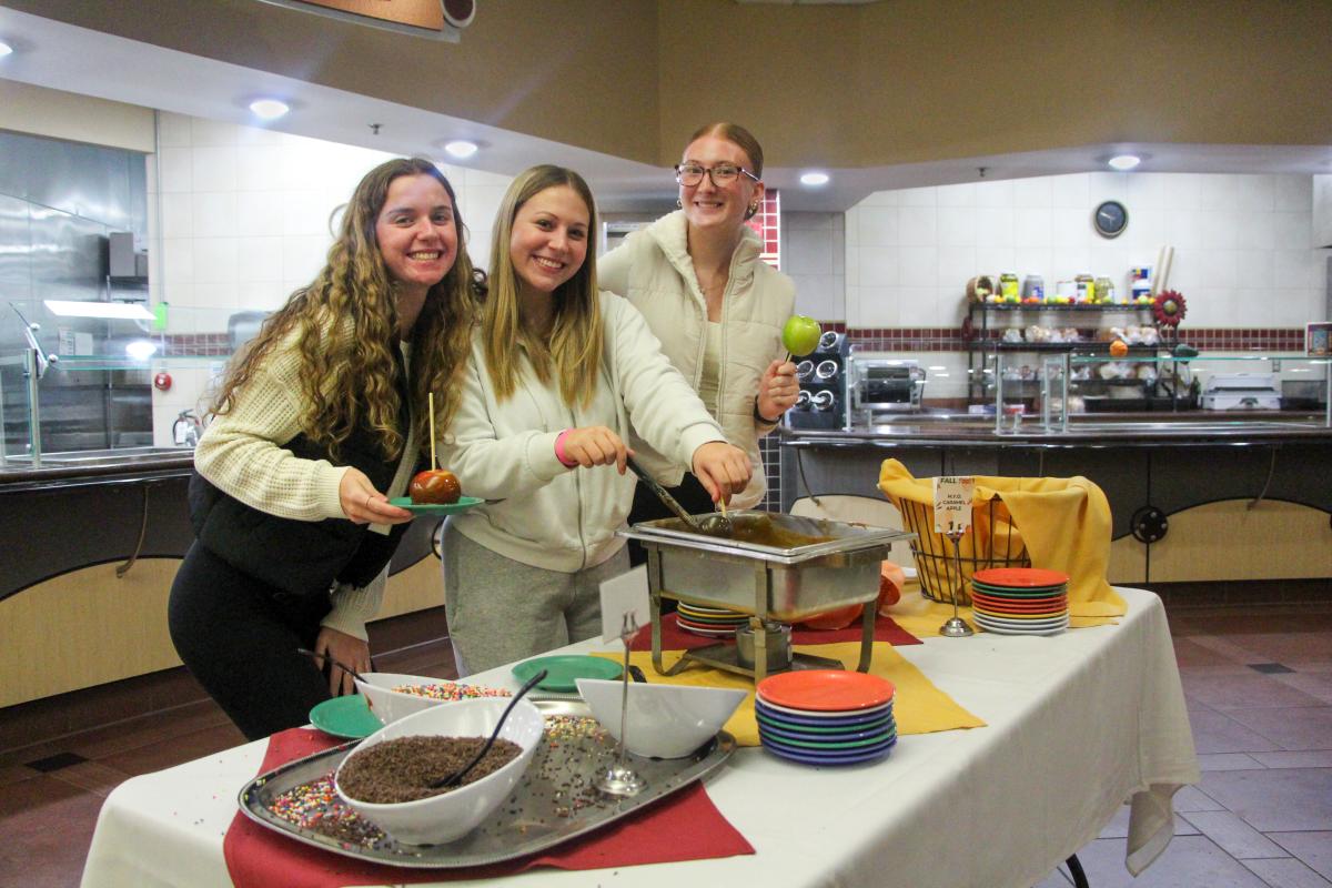 Three students enjoying food in the dining hall.